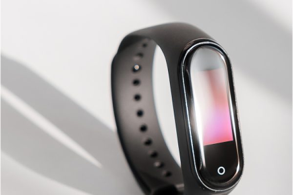 Montre connecté noir avec écran et bouton intégré sur fond clair avec ombre de la montre